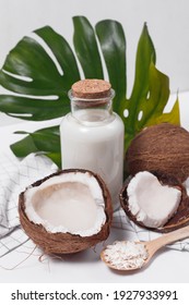 Coconut milk in a glass bottle. Whole and cracked coconut on white background