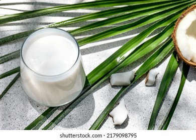 Coconut Milk In Glass And Half Of Coconut On Palm Leaf Background. Vegetable Milk, Lactose Free Non Dairy Healthy Drink. Vegan Food.