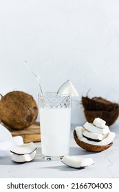 Coconut Milk In A Glass And Pieces Of Tropical Fruit On The Table. Natural Source Of Antioxidants, Plant Alternative. Vertical View