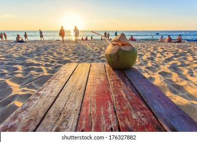 Coconut on the table at sunset beach in Thailand