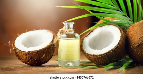 Coconut palm oil in a bottle with coconuts and green palm tree leaf on brown background. Coco nut close-up. Healthy Food, skin care concept. Skincare treatments. Vegan food