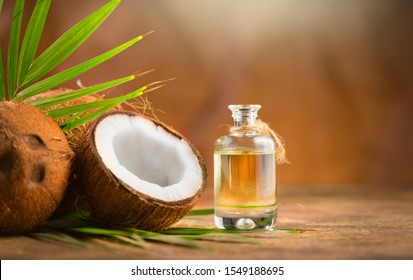 椰子棕榈油装在瓶子里，棕色背景上有椰子和绿色的棕榈树叶。可可坚果特写。健康食品，皮肤护理概念。纯素食品。护肤护理。芳香疗法