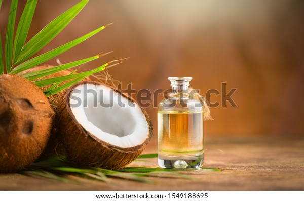 Coconut palm oil in a bottle with coconuts\
and green palm tree leaf on brown background. Coco nut closeup.\
Healthy Food, skin care concept. Vegan food. Skincare treatments.\
Aromatherapy