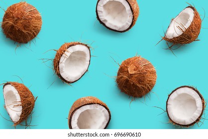 Coconut pattern on a blue background. Half and whole coconuts. Repetition concept. Top view
