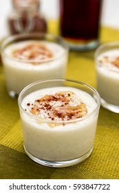 Coconut rice pudding vertical view. Coconut flavored rice pudding dessert with maple syrup drizzle on top and sprinkled cinnamon served in glass bowl. Portrait orientation.