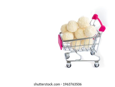 coconut round candies in a mini shopping basket, isolate on a white background. Supermarket shopping concept. full cart of sweets. High quality photo