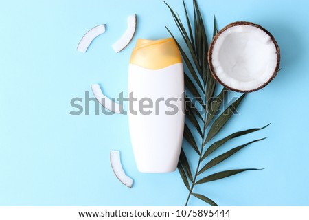 
coconut shower gel, palm leaf and fresh coconut on a colored background. skin care, firmness and youth. flatlay