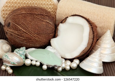 Coconut spa products with moisturiser, exfoliating scrubs, sea shells and pearls over bamboo background.