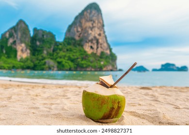 Coconut water drink with a straw on sandy tropical Railay beach with turquoise water and rock formations in Krabi province, Thailand. Refreshment summer drink - Powered by Shutterstock