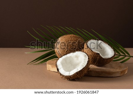 Coconuts with palm leaf over brown background. Tropical fruit.