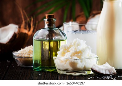 Coconuts products - mct butter, oil, milk, oil, shavings on wooden background. Copy space. Hair, skin and body treatment concept