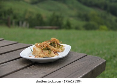 Cod Fish, Fried Bacalao With Onion, On White Plate, Wooden Table In Nature Traditional Dish Of Spain, Roasted Meal, Sidreria Side Dish In Basque Country 