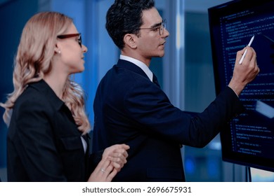 Code breakthrough achieved. Smiling senior developer points to a successful code segment on screen, sharing the solution with his colleague during a late night pair programming session.