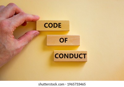 Code of conduct symbol. Concept words 'Code of conduct' on wooden blocks on a beautiful white background. Businessman hand. Business and code of conduct concept. Copy space.