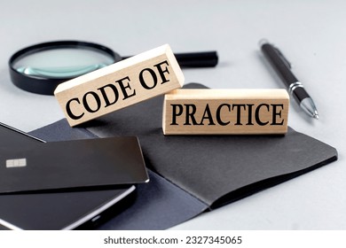 CODE OF PRACTICE text on a wooden block on black notebook , business concept