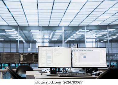 Code running on computer displays in empty data center workspace, used for troubleshooting rackmounts. Binary script running on desktop PC monitors upgrading mainframes systems in server room