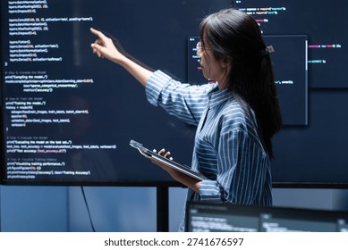Coding Meeting Collaboration Teamwork in Tech Office at night. Asian Female Software Developer pointing to screen while presenting code on screen brainstorming, Discussing with Colleagues in office.