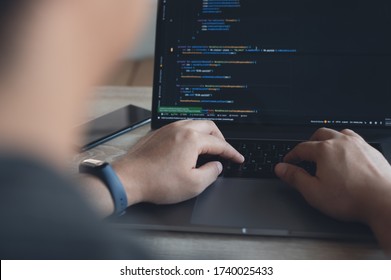 Coding programmer, digital software technology developer or software engineer working on laptop computer programming code on screen with mobile smart phone on table,