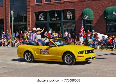 Cody, Wyoming, USA - July 4th, 2009 - Then Wyoming Secretary Of State Max Maxfield With His Wife Gayla Maxfield Riding In A Convertible And Waving While Participating In The Independence Day Parade