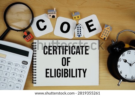 COE Certificate of Eligibility text written on notepad with house model, alarm clock and magnifying glass on wooden background