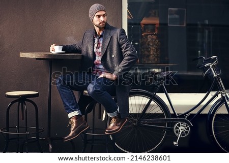 Coffee is always a good idea. Shot of a handsome young man in winter wear having a beverage at a sidewalk cafe.