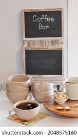 Coffee Bar Setup With Pink Speckled Cups And Blackboard Sign In Vertical Format.  Focus On Cup Of Coffee In Foreground.