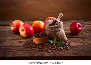 Coffee beans in a bag, scattered on a wooden table and a number of red apples. Free space for your text - Powered by Shutterstock