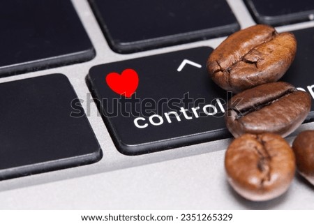Coffee beans close to control key with red heart icon, concept of regular blood pressure testing in people who drink coffee regulating during office work