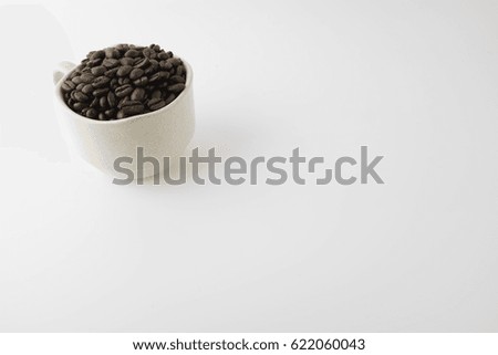 Coffee beans in a cup of tea over white background