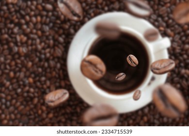 Coffee beans fall into a cup of coffee. White cup with coffee on the background of coffee beans. Energy drink, caffeine. Selective focus - Shutterstock ID 2334715539