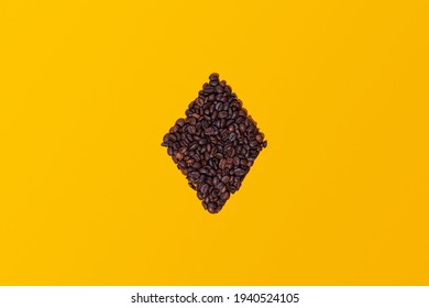 Coffee beans grouped together forming the figure of a playing card diamond isolated on a yellow background viewed from above. There is space for text or logos. - Powered by Shutterstock