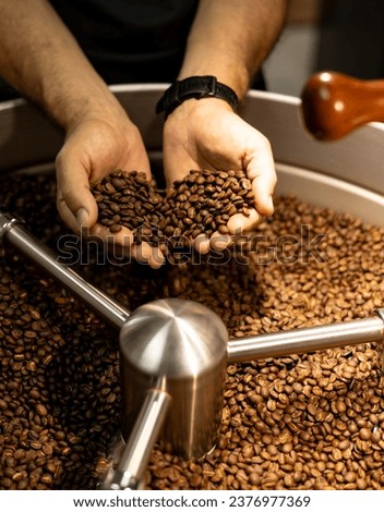 Coffee beans in a hand over coffee roaster.