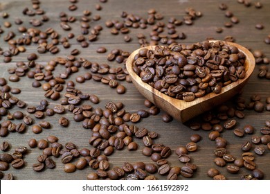 Coffee beans in a heart-shaped plate, coffee beans scattered on a wooden table