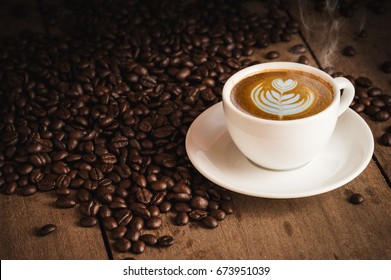 Coffee Beans And Hot Cofee Cup With Latte Art On Wooden Background. Side View With Copy Space For Your Text