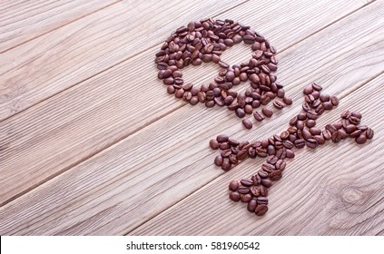 From coffee beans laid out a symbol of skull and bones. Coffee kills. Wooden background