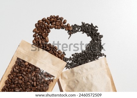 Coffee beans and leaf tea packed in a paper bag for storage and a mock-up of a white tag for a logo, price tag, advertising. Scattered tea and coffee beans on a heart-shaped table