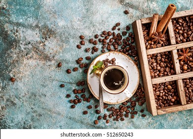 Coffee Beans In Old Wooden Box, And Ceramic Cup Of Fresh Making Coffee Over Blue Stone Background. Top View