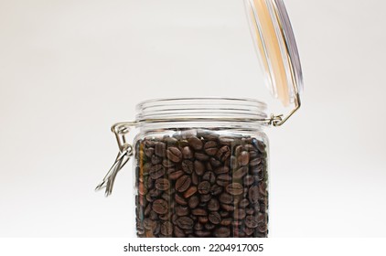 Coffee beans packed in a clear glass jar with a lid open close-up white background - Powered by Shutterstock