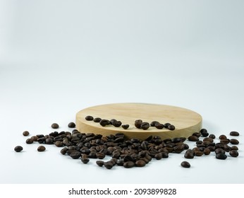 Coffee Beans Scattered On A Round Wooden Plank Isolated On A White Background. Product Placement Concept.