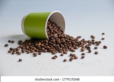Coffee Beans Spilled Out Of A Green Paper Cup
