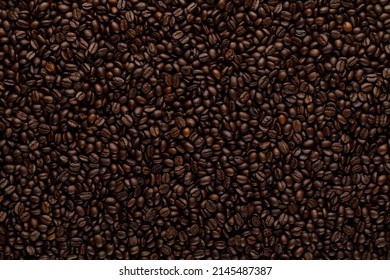 Coffee beans texture in roasting process. Dark brown abstract background