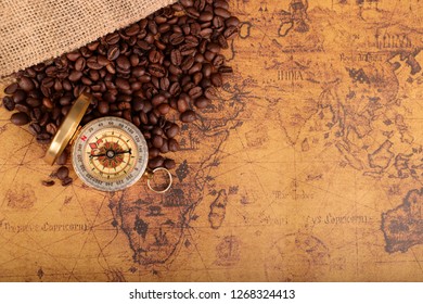 Coffee Beans and Vintage compass on an old world map - trade and explorer concept 