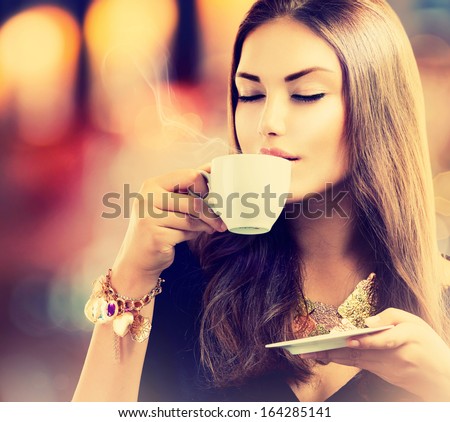 Coffee. Beautiful Girl Drinking Tea or Coffee in Cafe. Beauty Model Woman with the Cup of Hot Beverage. Warm Colors Toned 