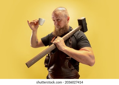 Coffee break. Comic image of bearded bald man, blacksmith leather apron or uniform isolated on yellow background. Concept of labor, retro professions, power, beauty, humor. Funny meme emotion