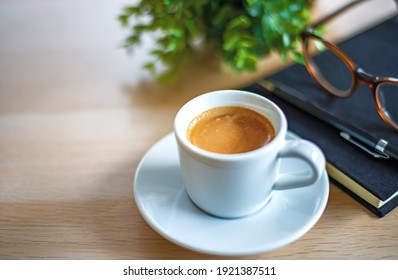 coffee break concept, close-up a cup of espresso coffee with black notebook , pencil and the glasses on white table. soft tone color picture - Powered by Shutterstock