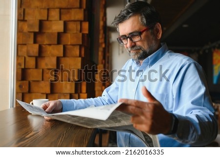 coffee break. man drinking coffee and reading newspaper in cafe bar.