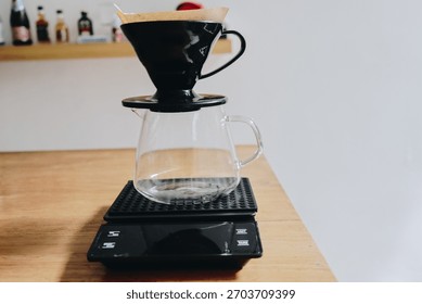 Coffee brewing setup with a digital scale, clear glass carafe, and a black pour-over device.