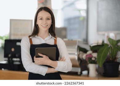 Coffee Business owner Concept - attractive young beautiful caucasian barista in apron smiling at camera in coffee shop counter. - Shutterstock ID 2262367341