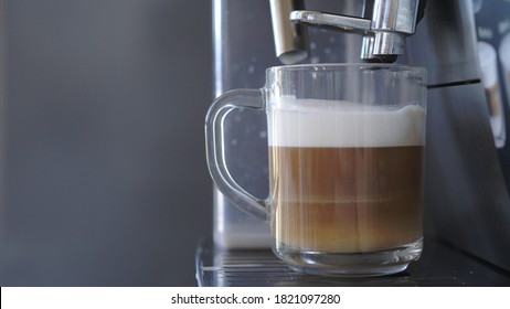 Café por máquina de café en taza transparente de vidrio, café con leche
