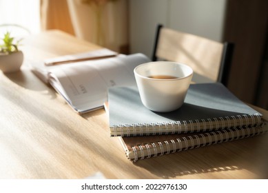 At coffee cafe, Diary book and Planner Paper place on work desk to meeting appointment. Calendar for organizer to plan timetable, daily, agenda, and management job. Planner and 2022 Calendar Concept.